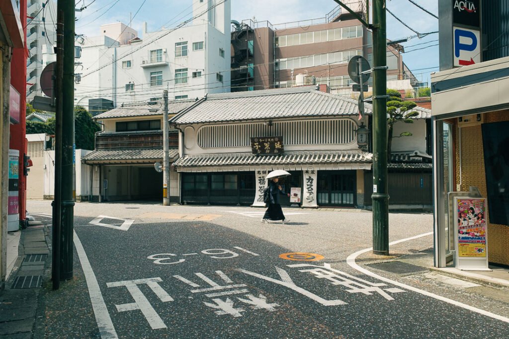 une femme marche dans la rue devant une enseigne japonaise