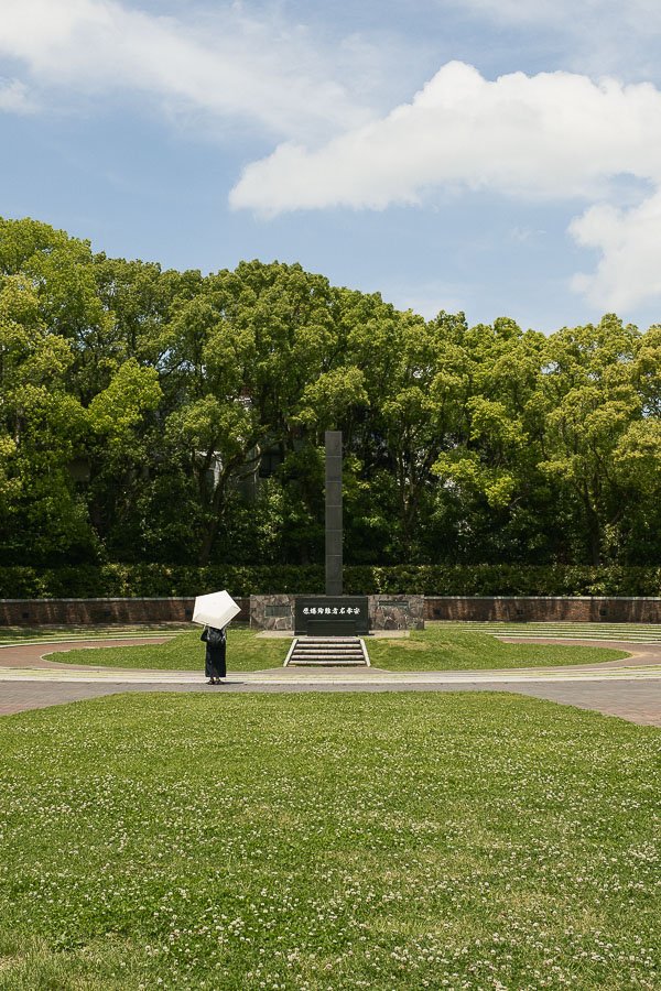 Une femme avec un parapluie devant le mémorial de la paix à Nagasaki